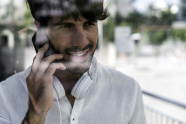 Portrait of young man on cell phone in the city - GIOF04847