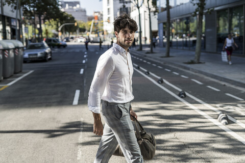 Junger Mann in der Stadt unterwegs beim Überqueren der Straße, lizenzfreies Stockfoto