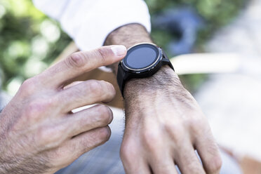 Close-up of man using smartwatch outdoors - GIOF04861