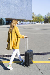 Rear view of woman with suitcase in the city on the go - GIOF04866