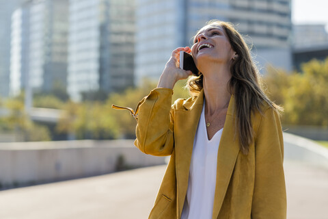 Lachende Frau am Mobiltelefon in der Stadt, lizenzfreies Stockfoto