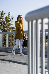 Frau mit Mobiltelefon auf einer Brücke - GIOF04887