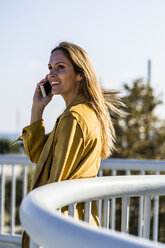 Lächelnde Frau mit Mobiltelefon auf einer Brücke - GIOF04889