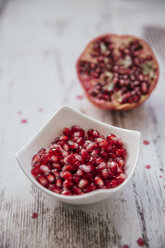 Schale mit Granatapfelkernen und halbem Granatapfel im Hintergrund - MBEF01444