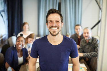 Portrait of confident businessman standing while colleagues in background at office - MASF10179