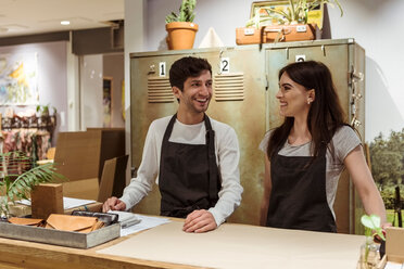 Smiling male and female coworkers standing at checkout counter - MASF10203