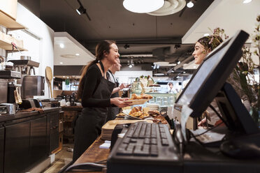 Verkäuferin, die einem Kunden im Café Essen serviert - MASF10235