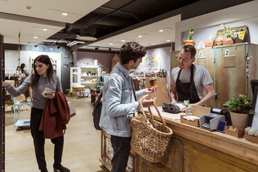 Male customer buying merchandise from salesman at boutique - MASF10254