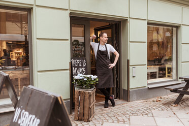 Full length of salesman standing at doorway of cafe - MASF10260