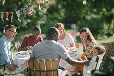 Glückliche Mehrgenerationenfamilie beim gemeinsamen Mittagessen im Garten während eines Gartenfestes - MASF10276