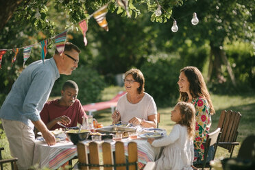 Älterer Mann und Enkelin unterhalten sich beim Mittagessen mit der Familie im Hinterhof während einer Party - MASF10277