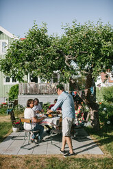 Mehrgenerationenfamilie beim gemeinsamen Mittagessen auf der Terrasse während eines Gartenfestes - MASF10279