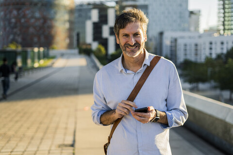 Portrait of smiling mature man with cell phone in the city stock photo