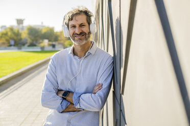 Portrait of smiling mature man listening to music with headphones - GIOF04925