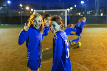 Porträt selbstbewusstes Mädchen, das Fußball spielt und den Daumen nach oben streckt - HOXF04181