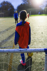 Mädchen spielt Fußball auf einem Feld bei Nacht - HOXF04186