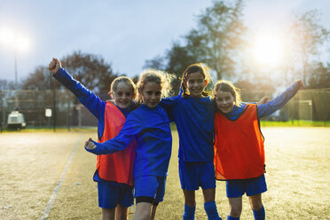 Portrait confident girls soccer team cheering on field - HOXF04192