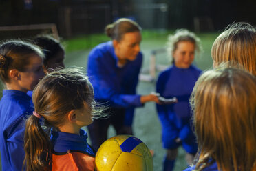 Girl soccer players listening to coach in huddle - HOXF04195