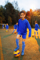 Portrait confident girl practicing soccer on field - HOXF04199
