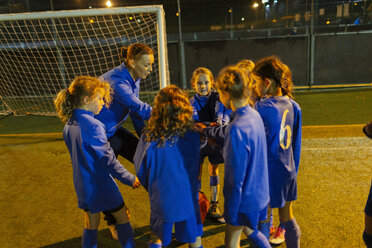 Fußballtrainer und Mädchenfußballmannschaft auf dem Spielfeld bei Nacht - HOXF04203