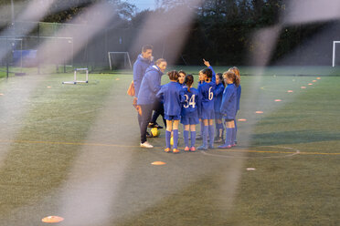 Soccer coaches and girl soccer team talking on field - HOXF04205