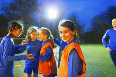 Porträt einer selbstbewussten Fußballspielerin auf dem Feld mit ihrer Mannschaft bei Nacht - HOXF04214