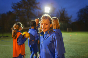 Portrait smiling, confident girl soccer player on field at night - HOXF04219