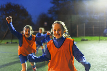 Porträt begeisterter Mädchenfußballerinnen, die nachts auf dem Spielfeld jubeln - HOXF04225