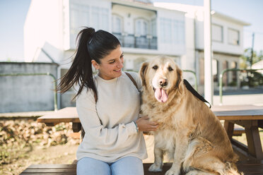 Smiling young woman with her Golden retriever dog resting outdoors - RAEF02226