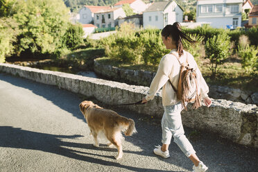 Woman walking with her golden retriever dog on a road - RAEF02227