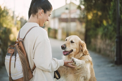 Glückliche junge Frau, die mit ihrem Golden Retriever Hund im Freien spielt - RAEF02237