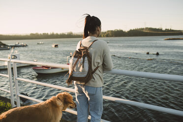 Frau schaut mit ihrem Hund auf das Meer - RAEF02243