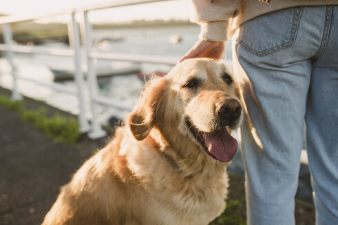 Nahaufnahme einer Frau mit ihrem Golden Retriever Hund am Wasser - RAEF02245