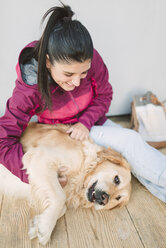 Glückliche junge Frau streichelt und spielt mit ihrem Golden Retriever Hund - RAEF02264