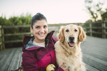 Porträt einer glücklichen jungen Frau mit ihrem Golden Retriever Hund im Freien - RAEF02267