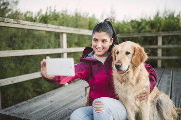 Lächelnde junge Frau macht ein Selfie mit ihrem Hund - RAEF02268