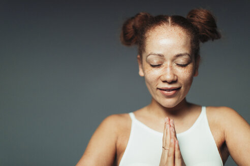 Porträt heitere Frau mit Sommersprossen meditiert mit geschlossenen Augen - CAIF22383