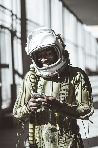 Lächelnder Astronaut im Raumanzug mit Smartphone, lizenzfreies Stockfoto