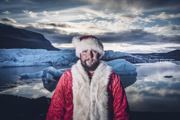 Island, Porträt eines lächelnden, als Weihnachtsmann verkleideten Mannes auf einem Gletscher - OCMF00172