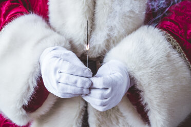 Hände des Weihnachtsmanns, der eine brennende Wunderkerze hält, Nahaufnahme - JCMF00031
