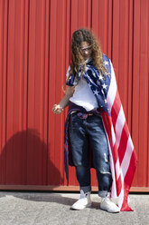 Mädchen an roter Wand mit amerikanischer Flagge stehend - ERRF00170