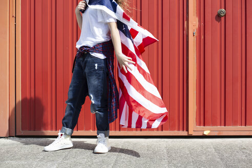 Mädchen an roter Wand mit amerikanischer Flagge stehend - ERRF00171