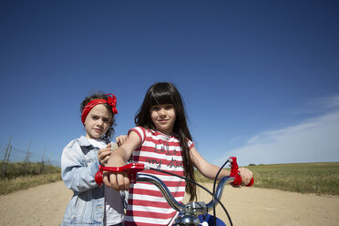 Zwei Mädchen mit Fahrrad auf Weg in abgelegener Landschaft - ERRF00176