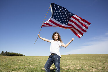 Mädchen hält amerikanische Flagge auf einem Feld in abgelegener Landschaft - ERRF00195
