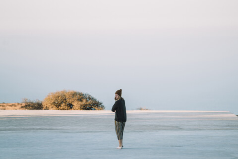 Rückansicht einer Frau, die vor dem Meer und dem Himmel steht, lizenzfreies Stockfoto