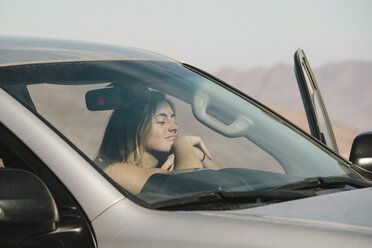 Woman resting in car seen through windshield during sunny day - CAVF57486