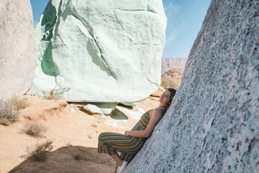 Porträt einer Frau, die sich in der Wüste an einen Felsen lehnt - CAVF57491