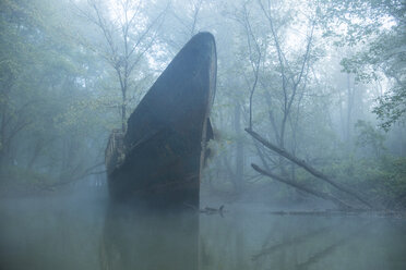 Abandoned boat on river in forest during foggy weather - CAVF57508