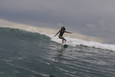 Woman surfing on sea against cloudy sky - CAVF57543