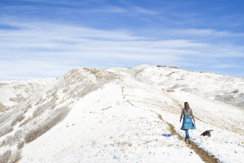 Rückansicht einer Frau, die auf einem Berg gegen einen bewölkten Himmel im Winter läuft - CAVF57562